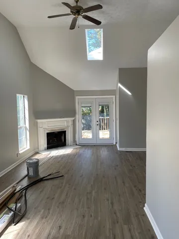 a view of an empty room with wooden floor and a window