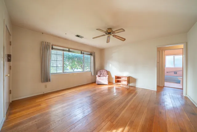 a view of empty room with wooden floor and fan