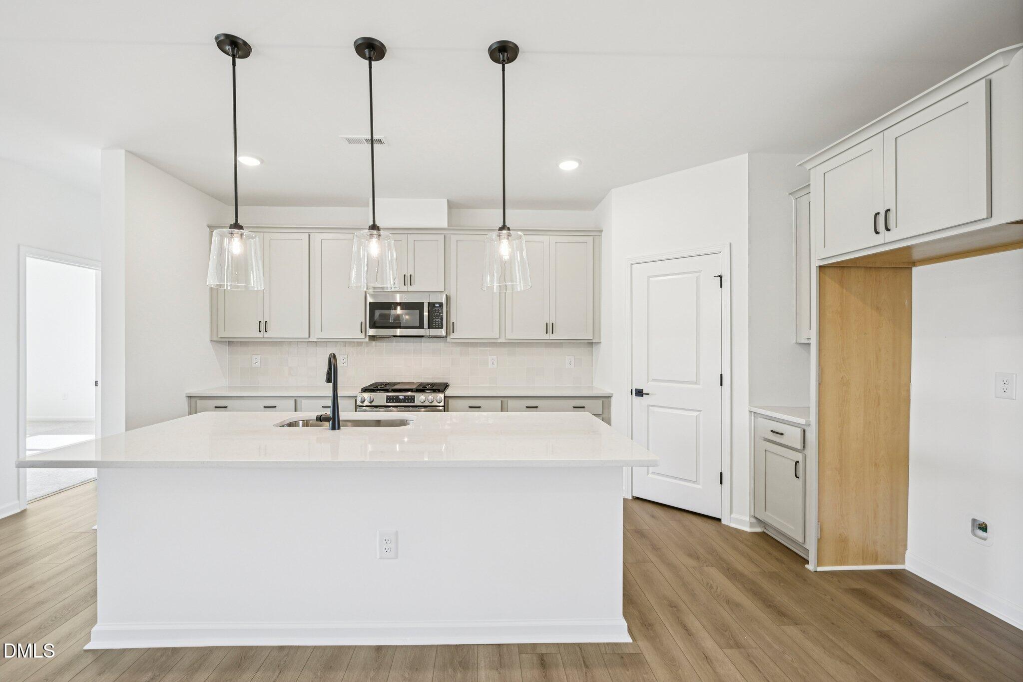 142 North Harvest Rdg Way, Unit HOMESITE 310 Clayton, NC 27520 - Photo 11 of 43 a kitchen with stainless steel appliances granite countertop a sink a refrigerator a stove and white cabinets with wooden floor