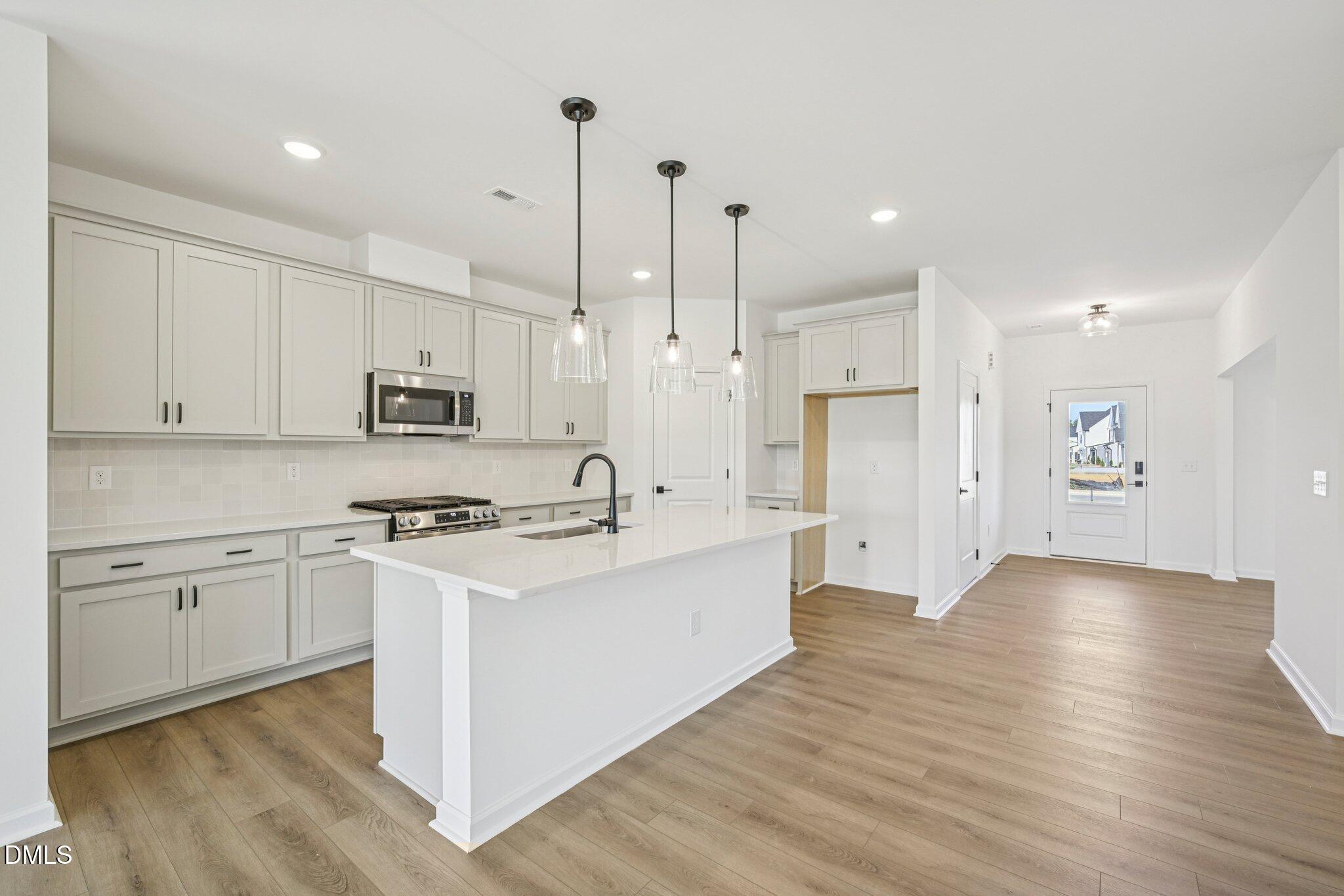142 North Harvest Rdg Way, Unit HOMESITE 310 Clayton, NC 27520 - Photo 12 of 43 a large kitchen with stainless steel appliances granite countertop a stove a sink a refrigerator and white cabinets with wooden floor