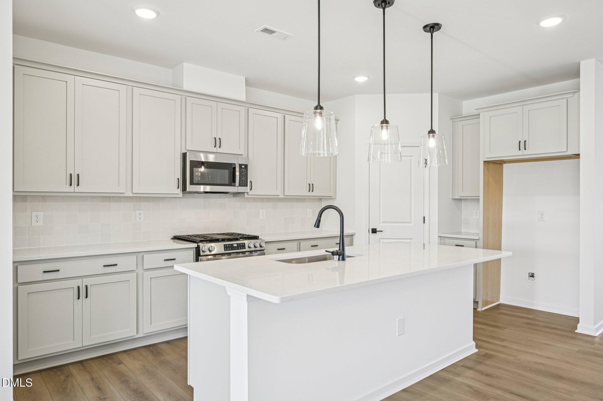 142 North Harvest Rdg Way, Unit HOMESITE 310 Clayton, NC 27520 - Photo 13 of 43 a kitchen with stainless steel appliances granite countertop a sink a microwave a stove and a refrigerator with wooden floor