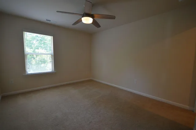 an empty room with a ceiling fan and a window