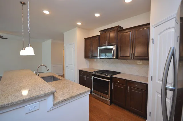a kitchen with granite countertop stainless steel appliances a sink stove top oven and refrigerator