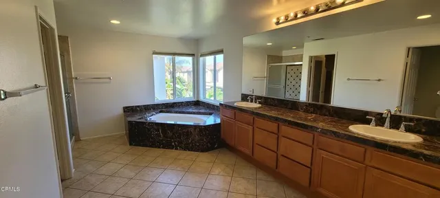 a bathroom with a granite countertop sink a mirror and a bathtub