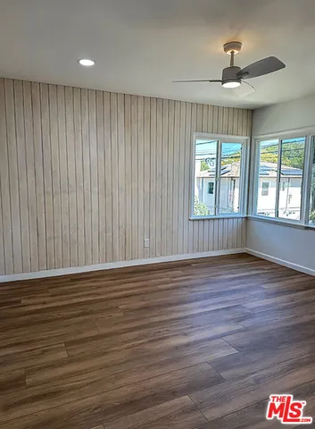an empty room with wooden floor closet and windows