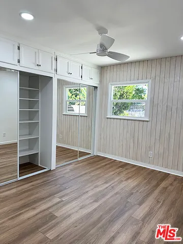 an empty room with wooden floor cabinet and windows
