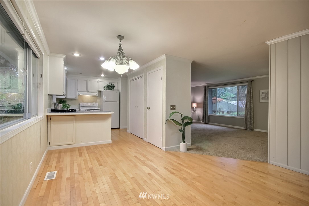 4321 196th Street Southeast Bothell, WA 98012 - Photo 12 of 40 a large kitchen with kitchen island a refrigerator a sink dishwasher a dining table and chairs with wooden floor
