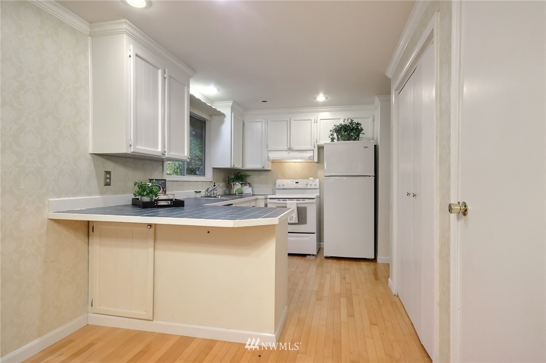 4321 196th Street Southeast Bothell, WA 98012 - Photo 15 of 40 a kitchen with refrigerator a stove a sink and white cabinets with wooden floor