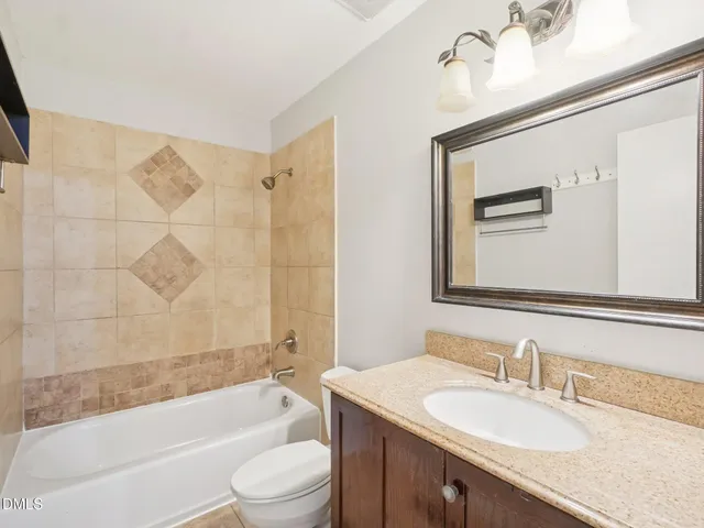 a bathroom with a granite countertop sink mirror toilet and bathtub