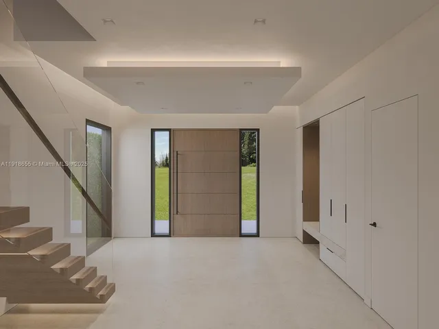 a view of an empty room with wooden floor and stairs