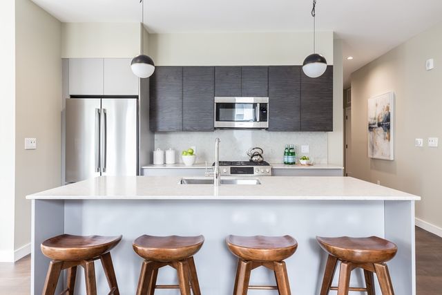 a kitchen with stainless steel appliances a table chairs refrigerator and microwave