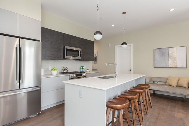 a kitchen with stainless steel appliances a stove a refrigerator a sink a dining table and chairs