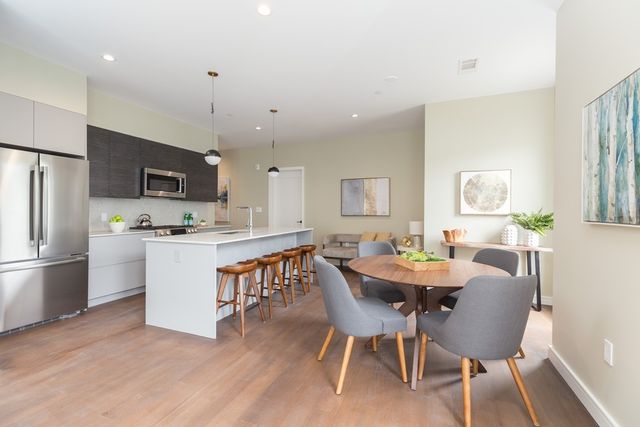 a kitchen with stainless steel appliances granite countertop a dining table chairs refrigerator and microwave