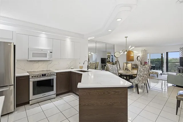 a kitchen with stainless steel appliances kitchen island granite countertop a sink a stove and a refrigerator