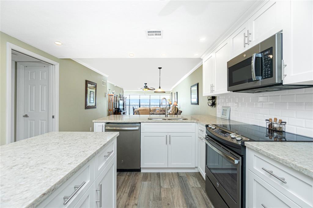 1591 Beach Road, Unit 403 Englewood, FL 34223 - Photo 23 of 61 a kitchen with stainless steel appliances granite countertop a sink stove and microwave