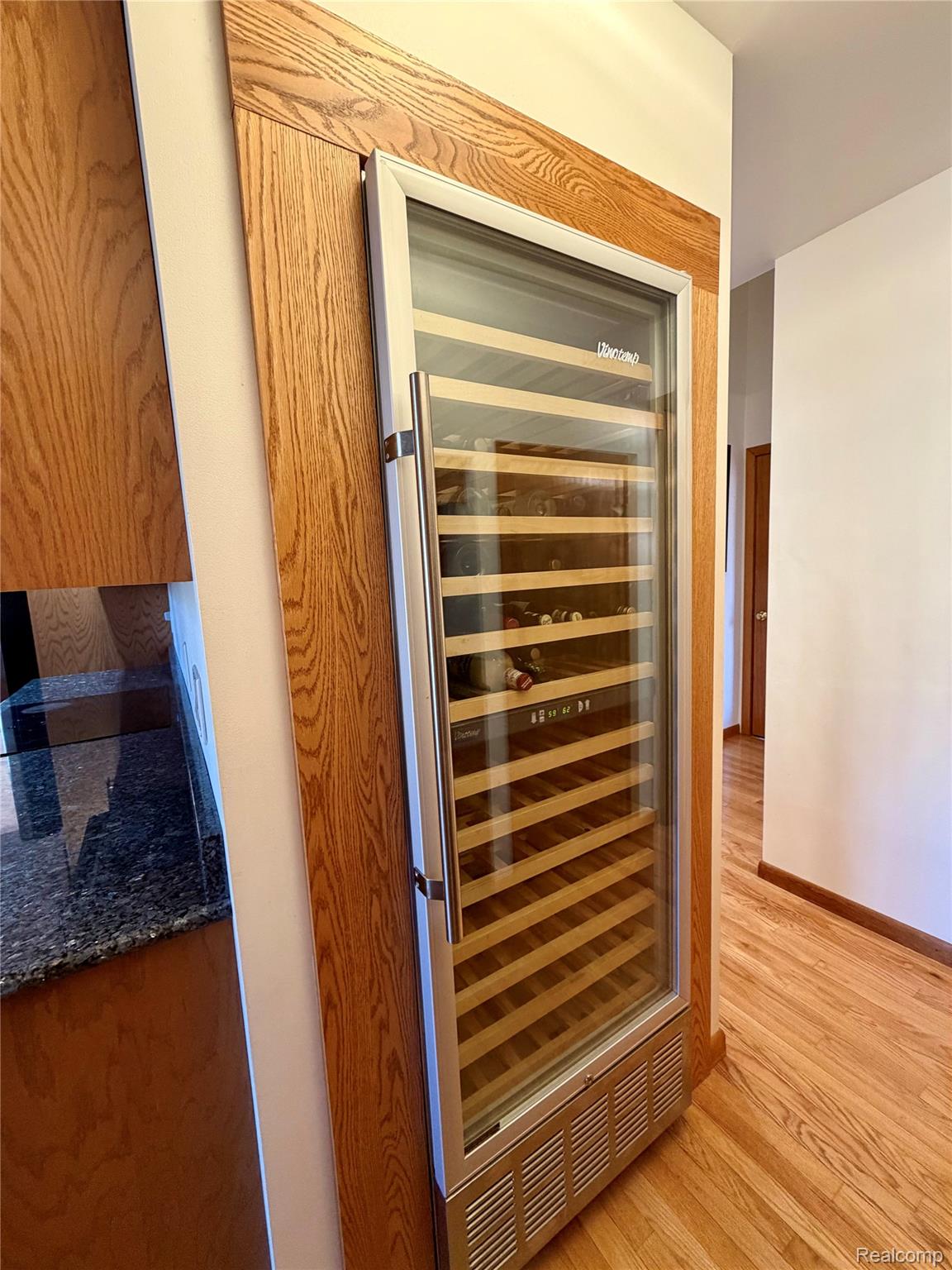10655 Beardslee Road Perry, MI 48872 - Photo 10 of 26 Detailed view of beverage cooler, light wood-style floors, and dark stone counters