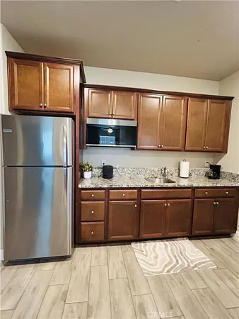 a kitchen with granite countertop wooden cabinets a refrigerator and a sink