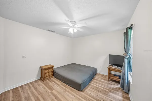a view of an empty room with wooden floor and a kitchen