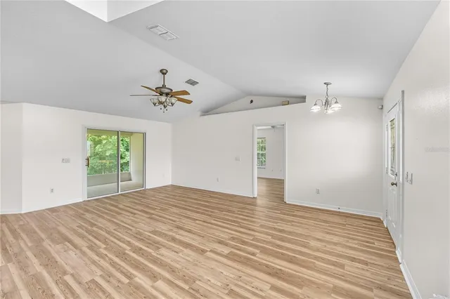 an empty room with wooden floor ceiling fan and windows
