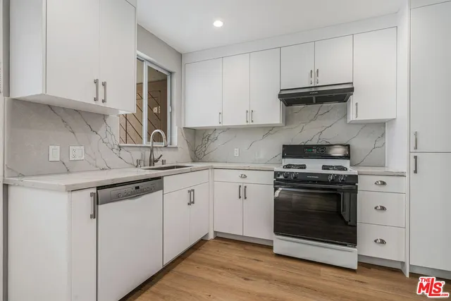 a kitchen with stainless steel appliances granite countertop a stove and a white cabinets