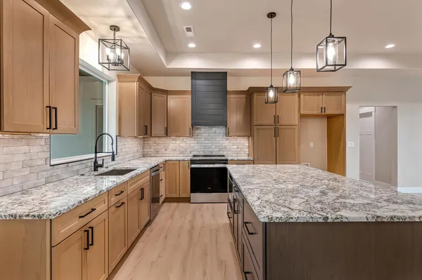 a large kitchen with granite countertop a sink a counter space appliances and cabinets