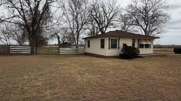 a view of a house with a yard and large trees