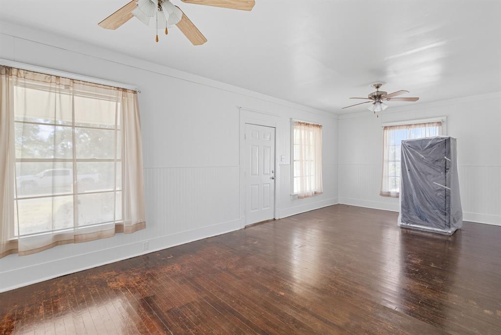 709 East 23rd Street Cisco, TX 76437 - Photo 4 of 17 an empty room with wooden floor chandelier fan and windows