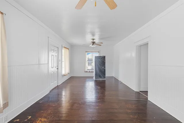an empty room with wooden floor chandelier and windows