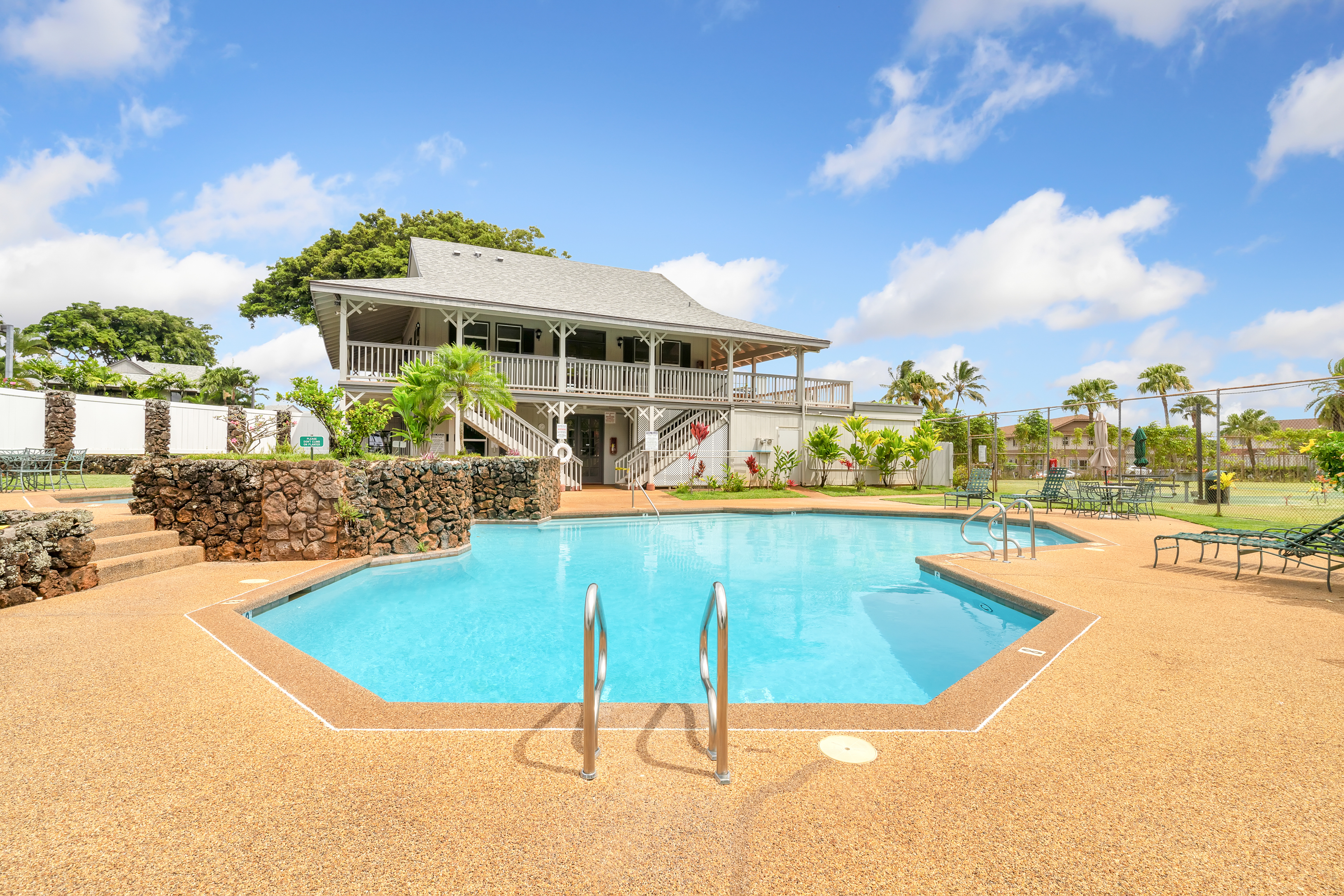 4121 Rice Street, Unit 402 Lihue, HI 96766 - Photo 2 of 20 a view of a swimming pool with a lawn chairs under an umbrella