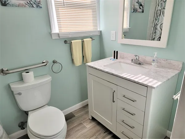 a bathroom with a granite countertop toilet sink and mirror