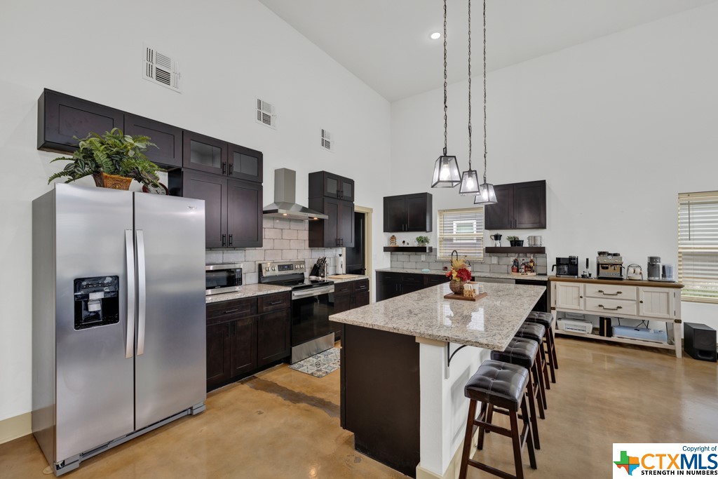 a kitchen with stainless steel appliances granite countertop a refrigerator a stove a microwave a sink dishwasher and white cabinets with wooden floor
