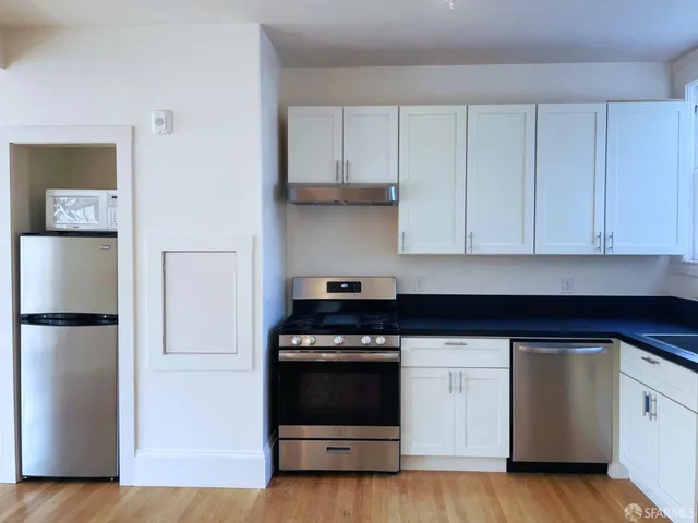 a kitchen with white cabinets and stainless steel appliances