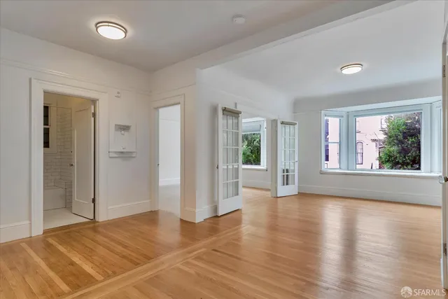 a view of an empty room with wooden floor and a window