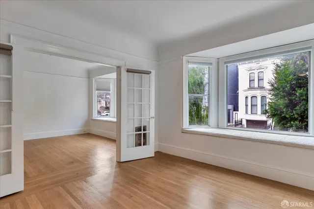 an empty room with wooden floor and windows