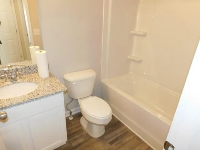 a bathroom with a granite countertop toilet and a sink