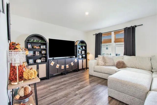 a living room with furniture a flat screen tv and a floor to ceiling window