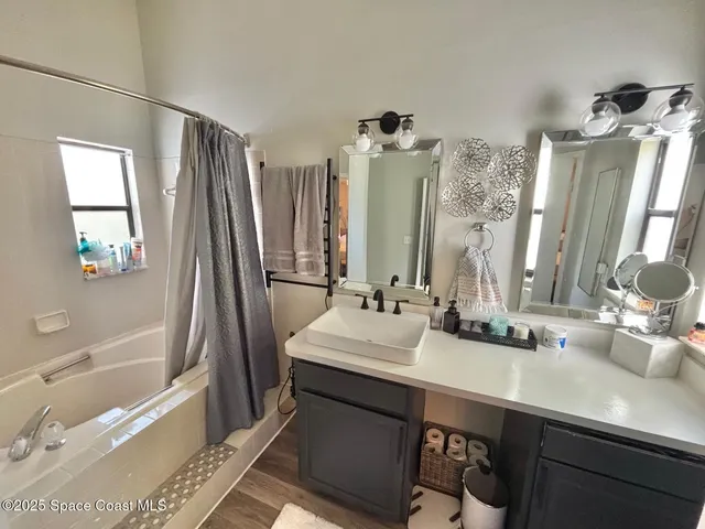 a bathroom with a double vanity sink a tub and a mirror