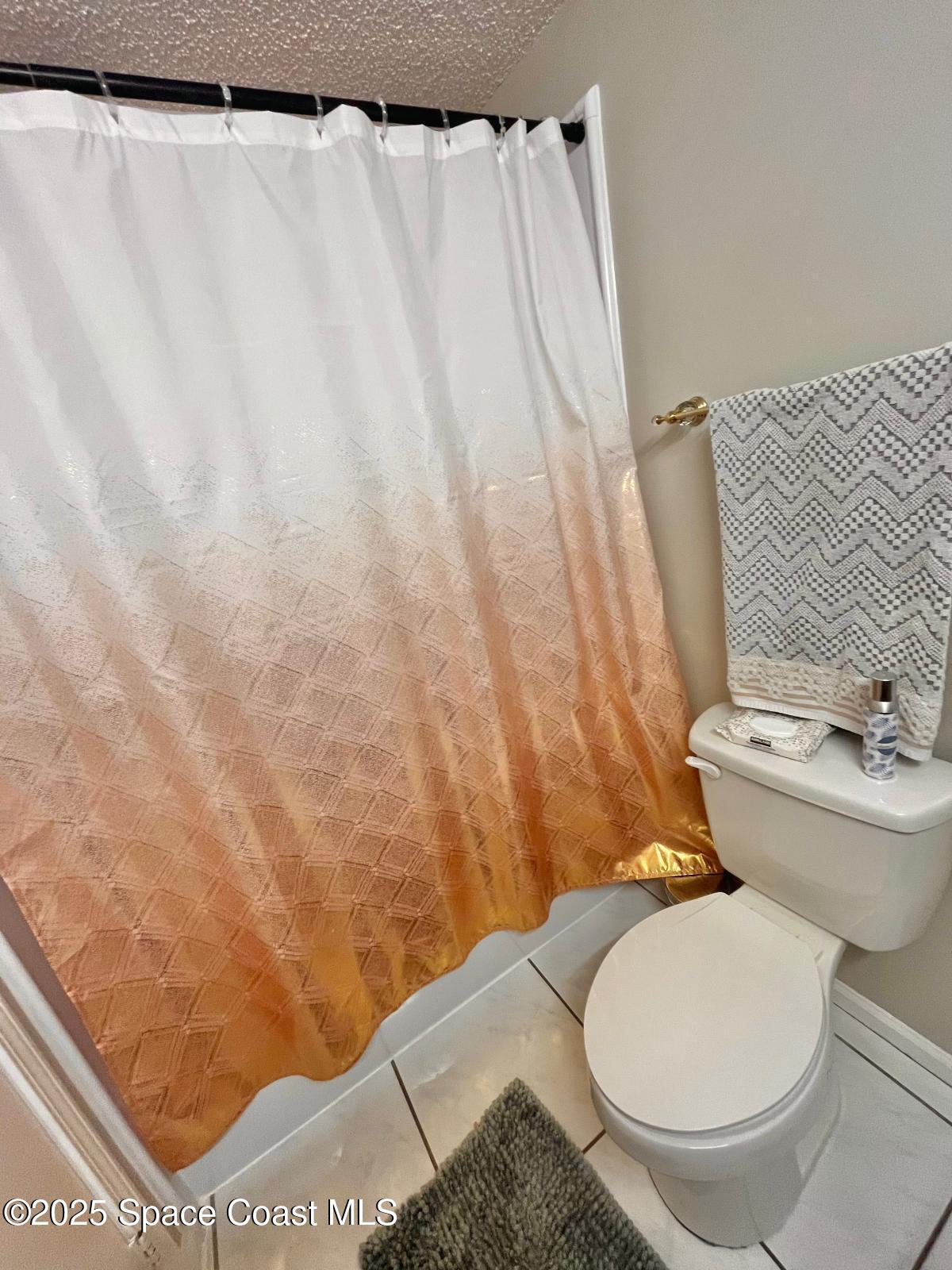 1626 Lara Street Northeast Palm Bay, FL 32907 - Photo 10 of 11 a white toilet sitting next to a shower curtain