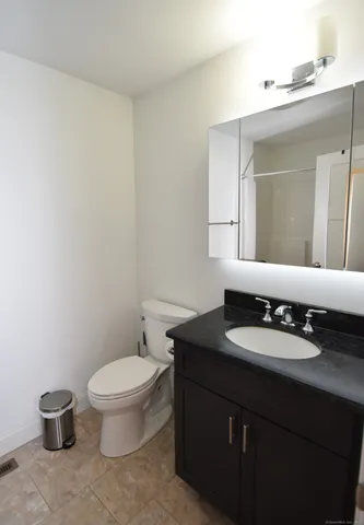 a bathroom with a granite countertop toilet sink and mirror