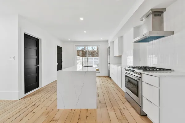 a large kitchen with stainless steel appliances granite countertop a stove and a refrigerator