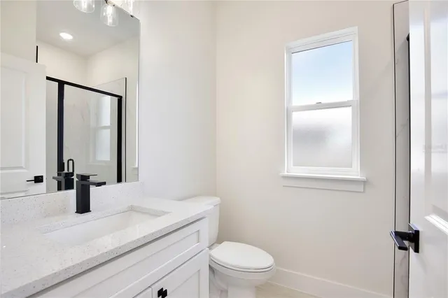 a bathroom with a granite countertop sink toilet and mirror