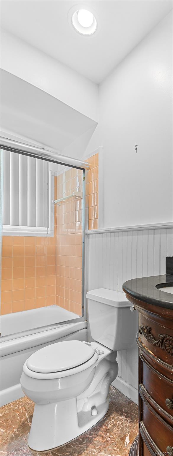 2345 Middlefield Road Trenton, MI 48183 - Photo 22 of 42 Bathroom featuring a vanity with a dark countertop, white toilet, tile flooring, and a tub with a sliding glass door