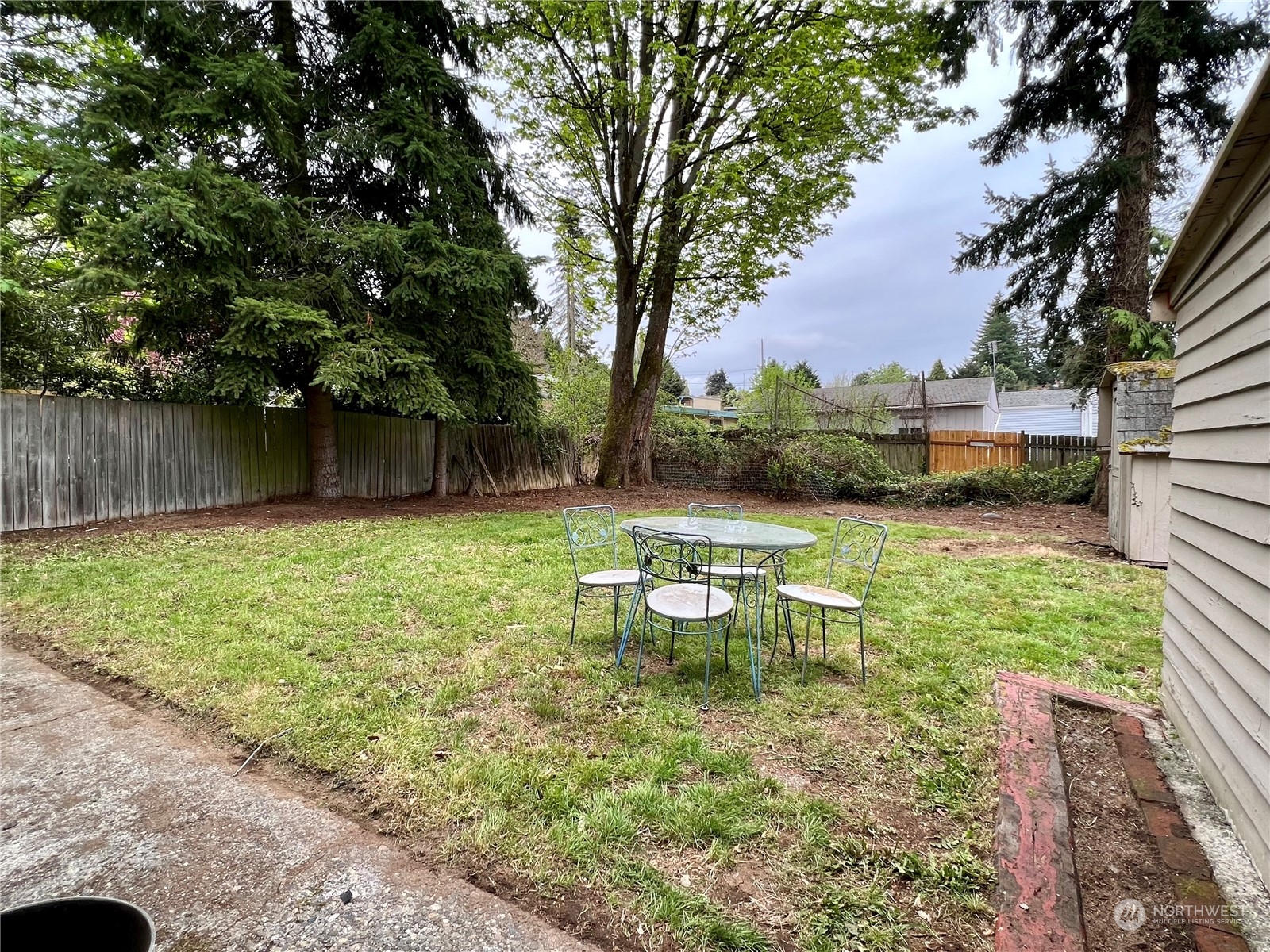 1031 Southwest 118th Street Seattle, WA 98146 - Photo 14 of 16 a view of a backyard with table and chairs potted plants and large tree
