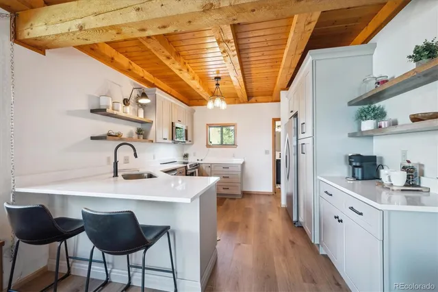 a kitchen with stainless steel appliances granite countertop a sink a stove and wooden floors