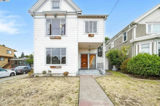 a view of a white house with large windows next to a road