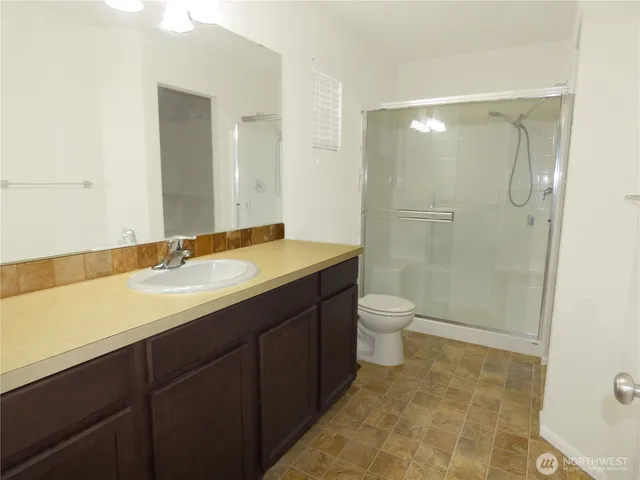 a bathroom with a granite countertop sink toilet a large mirror a shower and vanity
