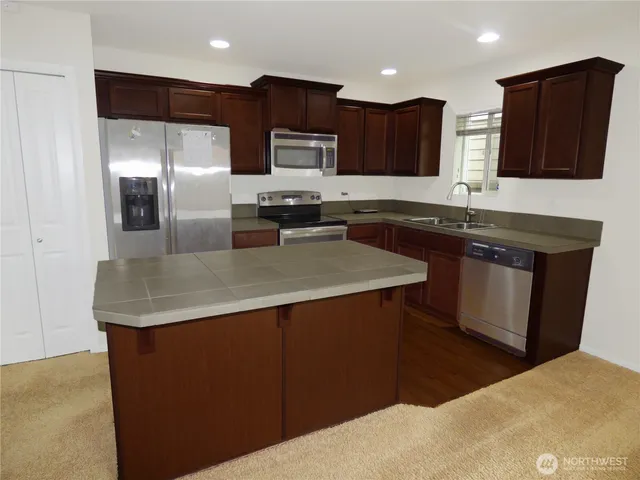 a kitchen with stainless steel appliances granite countertop a sink a refrigerator and a granite counter tops