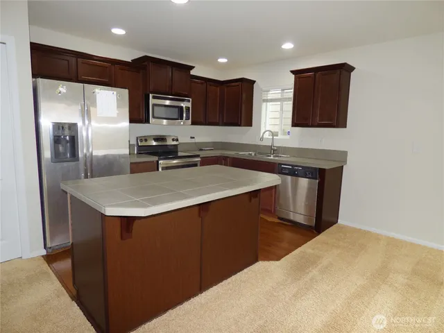 a kitchen with stainless steel appliances wooden cabinets a sink and a refrigerator