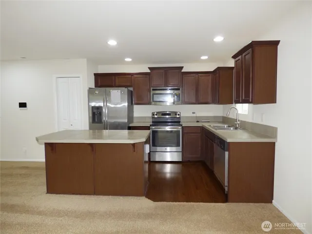 a kitchen with stainless steel appliances granite countertop a stove a sink and a refrigerator