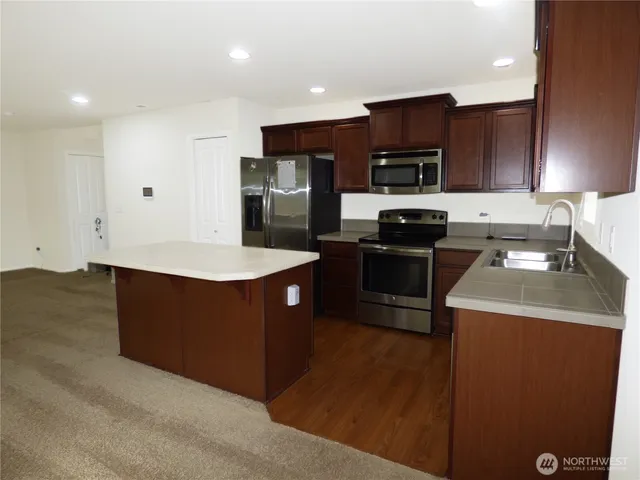 a kitchen with stainless steel appliances granite countertop a stove a sink and a refrigerator